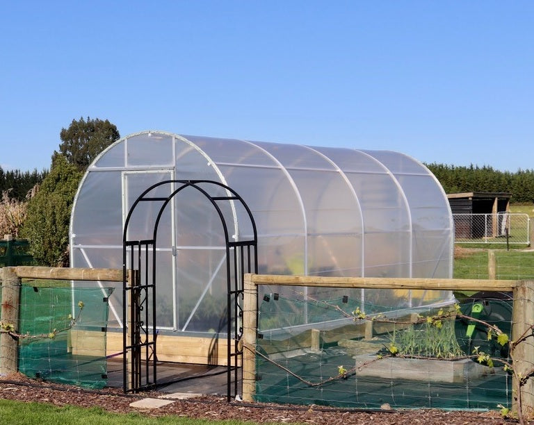 Duratough Tunnel House shown in gated vegetable garden with paddocks behind and clear blue sky.