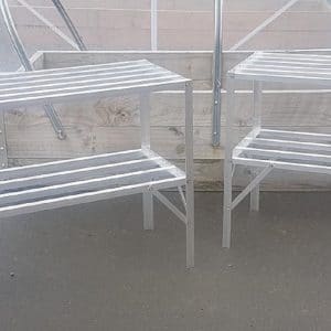 Two staging shelves showing durability and strength on concrete base with wooden planter behind.