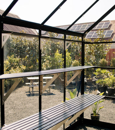 3 Tier glasshouse shelving unit installed in open sided glasshouse with garden in background.