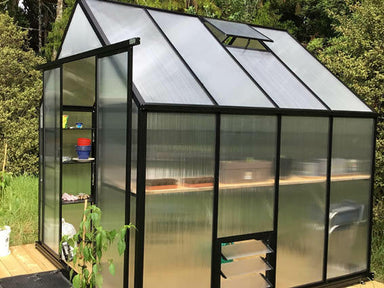 2.6m x 2.6m black framed polycarbonate greenhouse with double door open showing plants inside, bush background. 